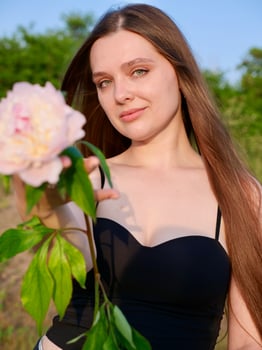 A woman in a black top holding a pink flower photo