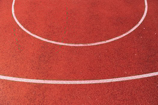 Smooth red track surface features clean white lines forming a perfect circle under clear blue skies, inviting athletes to train photo