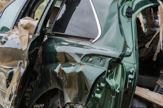 A green car involved in a severe crash displays significant structural damage, highlighting the dangers of traffic accidents photo