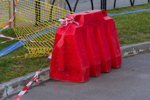 Bright red construction barrier and caution tape indicate a work zone, keeping pedestrians safe from ongoing city infrastructure maintenance photo