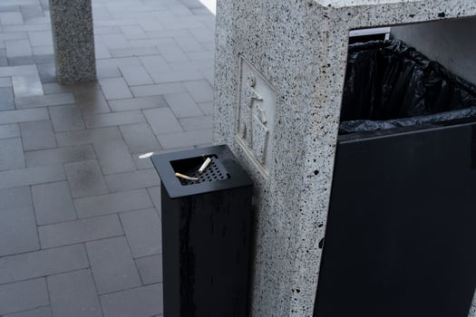 A public space features a solid waste container with a designated area for cigarette disposal, promoting environmental conservation efforts photo