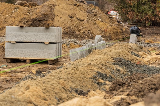 Construction workers repair a city street while gravel and concrete blocks are lined up beside the curb in an industrial area photo