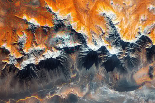 Snow capped mountain peaks rising from orange desert landscape aerial view photo