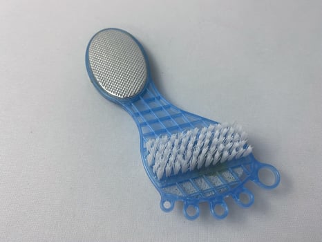 Closeup of a blue plastic foot care brush with scrubber and bristles on white background photo