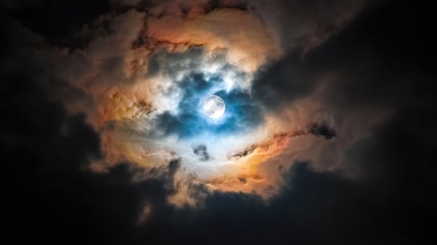 Mysterious Clouds Surrounding a Full Moon Illuminating the Night Sky with Colorful Rays of Light and Deep Shadows photo