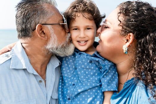 Happy family kissing smiling son outdoors, parents showing love and affection to their child photo