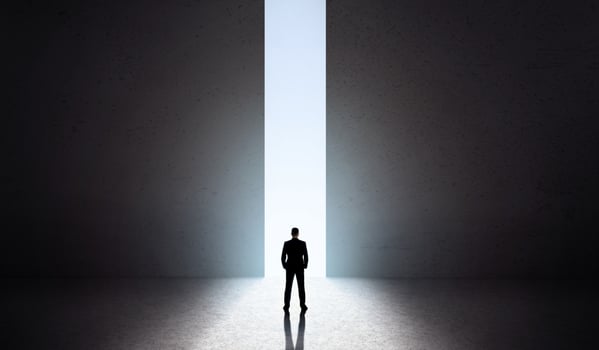 Male silhouette in front of huge opening concrete doors with blue light opening, panorama, copy space photo