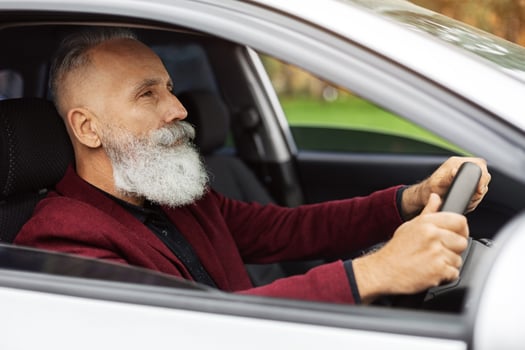 Concentrated senior grey-haired man with long beard enjoying his new safety car, driving home or to office, shot through open side window. Cars, auto, transportation concept photo