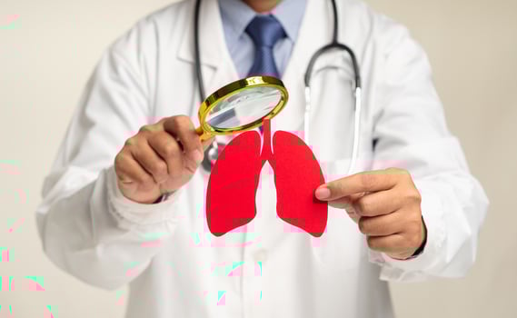 Doctor holding a magnifier looking at a lung shape symbol while standing in the hospital photo