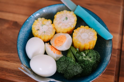 Colorful plate of nutritious food, eggs, corn, and broccoli ready to eat photo