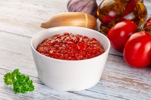 A bowl of tomato sauce next to a bottle of olive oil photo