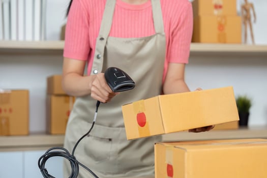 Small Business Inventory Management. Female entrepreneur scanning packages in her retail workspace. photo