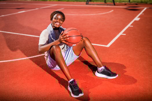Young black woman is sitting on basketball court. photo