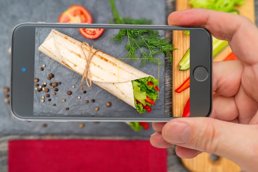 Vegetable roll for healthy lifestyle. Photo smartphone. Smartphone in hand. Roll on screen.