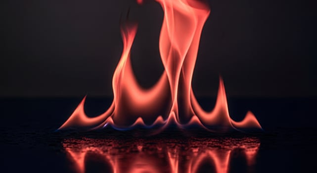 Vibrant red and orange flames with blue accents reflecting on a dark glossy surface photo