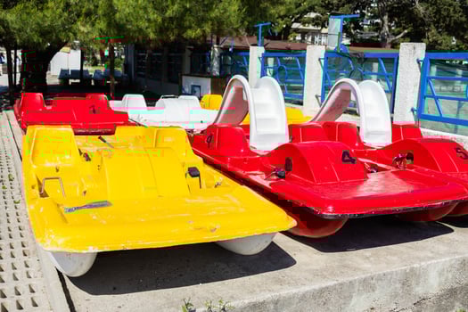 Colorful pedal boats on shore. Summer recreation, water sports, and tourism infrastructure close-up photo