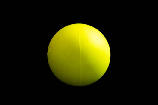 A vibrant green sphere resting on a polished wooden surface. isolated on black photo