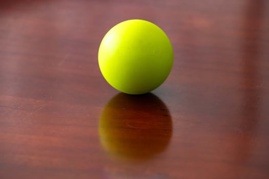 A vibrant green sphere resting on a polished wooden surface. portrait photo
