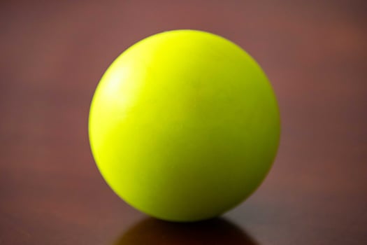 A vibrant green sphere resting on a polished wooden surface. photo