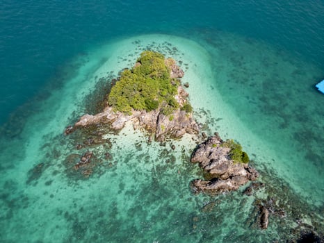Aerial view of tropical rocky shoreline with lush island scenery, beautiful seaside landscape featuring a tranquil rocky beach with harbor and clear blue waters. Exotic shoreline scenery. photo