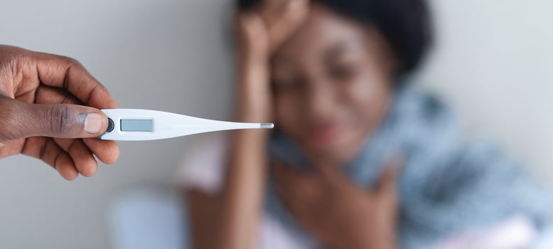 Cold, flue, coronavirus concept. Black woman suffering from fever, selective focus on thermometer in man hand. African american lady got flue, having headache, her husband taking care of her photo