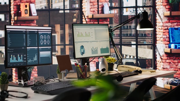Computer monitors on desk showing data analytics dashboards and performance charts. PC screens in company workspace displaying financial metrics and productivity data photo