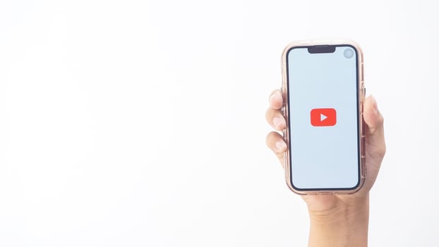 Yogyakarta, Indonesia, 2025 - Hand holding smartphone that shows Youtube application platform icon on the screen isolated on white background photo