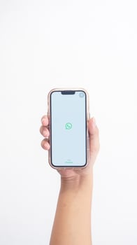 Yogyakarta, Indonesia, 2025 - Hand holding phone that shows WhatsApp application icon, a communication platform, on the screen isolated on white background photo