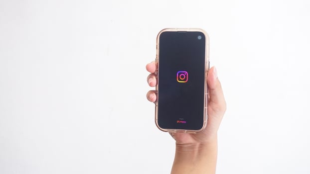 Yogyakarta, Indonesia, 2025 - Hand holdingHand holding smartphone that shows Instagram platform application icon on screen isolated on white background photo