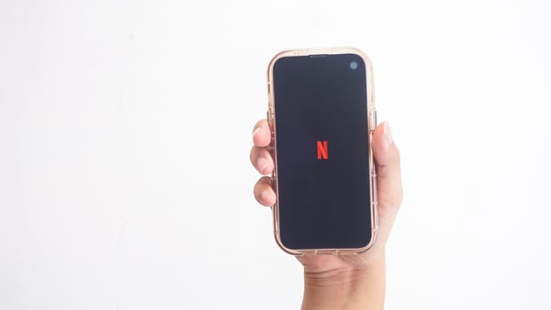 Yogyakarta, Indonesia, 2025 - Hand holding smartphone that shows Netflix application logo, a digital media streaming platform, on screen isolated on white background photo