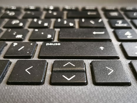 A close up of a computer keyboard with the word Pause on the top left. The keyboard is black and white with a few white keys photo