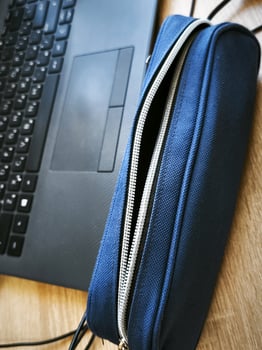A laptop is open to a blue case with a zipper. The laptop is on a wooden table photo