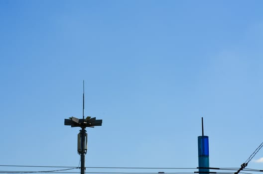 A tall pole with a light on top is next to a blue building. The sky is clear and blue photo