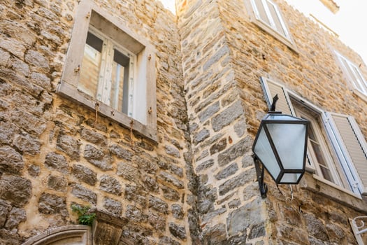Stone facade of old European building with vintage street lamp. Urban architecture, historical texture, and traditional window design. photo