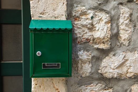 Green mailbox attached to stone wall. Postal service and communication concept. photo