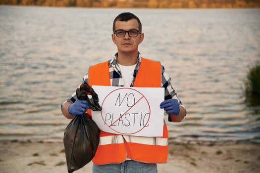 Text 'no plastic', on poster. Man volunteer is against Earth pollution by trash, outdoors photo