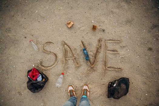 Top view, of sand with word save, trash on the ground, legs of the person, conception of ecology photo
