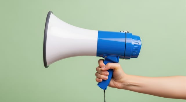 Human hand holding a blue and white megaphone for public announcement and communication photo