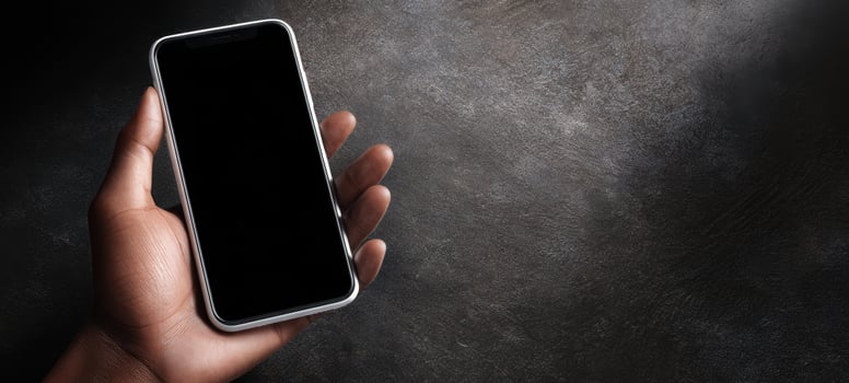 The smartphone held in a hand against a textured background. photo