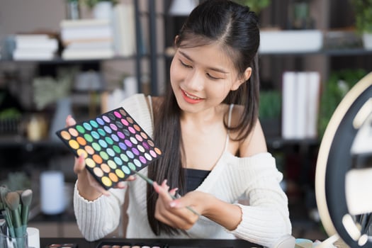asian woman is holding a makeup palette and looking at it. photo