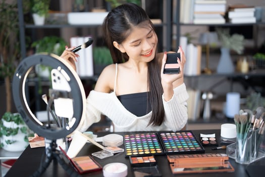 a woman is holding a phone and looking at makeup products photo