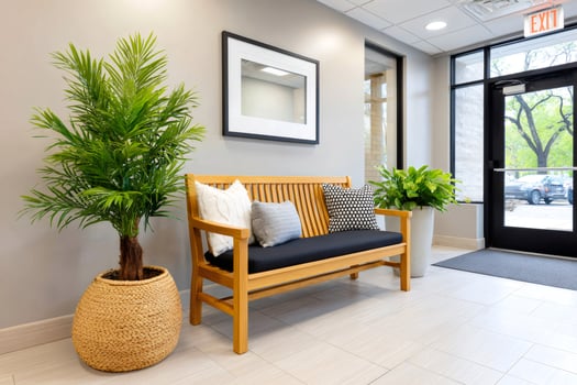 Wooden bench with cushions and plants decorating a modern office waiting area photo