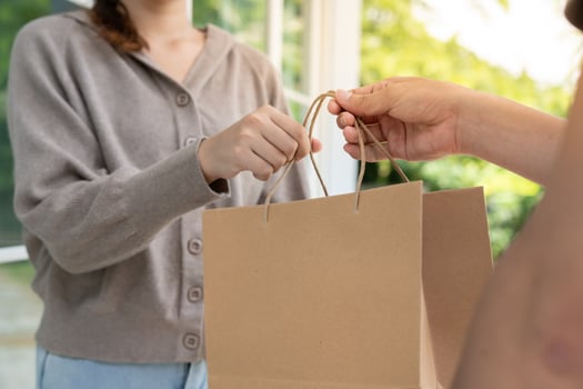 Happy smiling woman receives paper bag parcel of food from courier front house. Delivery man send deliver express. online shopping, paper container, takeaway, postman, delivery service, packages photo