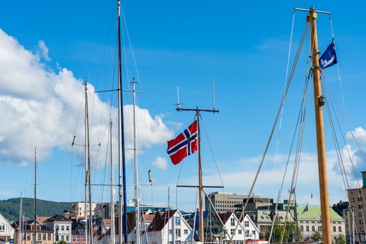 Bergen, Norway - July 9, 2024. Norwegian flag and yacht masts in harbor against clear blue sky photo
