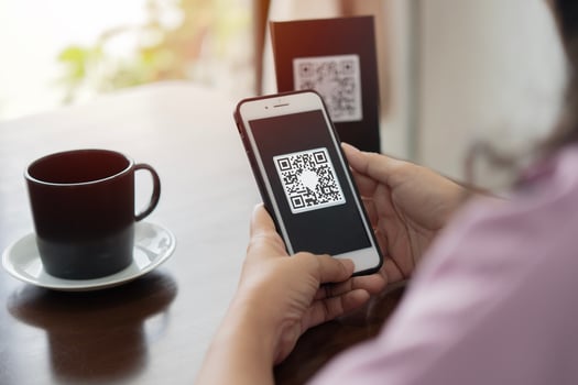 Close up of hands of young woman scanning qr code for cashless payment at cafeteria. photo