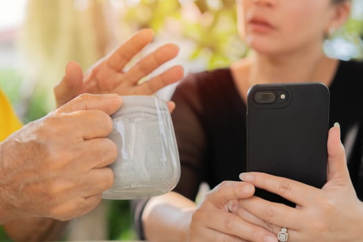 Close-up shot of an Asian woman using her smartphone while talk with her grandfather in the garden. photo
