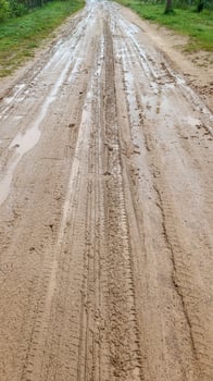 A dirty country road. After the rain, puddles, mud and traces of the car tires were formed. Shot on a phone photo