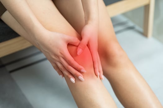 Knee Pain Relief. Woman holding her knee in discomfort while seated. photo