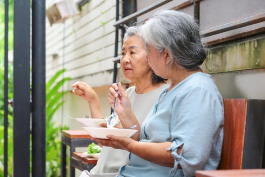 Senior Women Eating and Talking Together Indoors, Elderly Friends Sharing a Conversation and Lunch Together photo