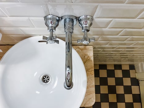 In this bathroom, there is a unique sink featuring three distinct faucets, complemented by an eyecatching checkered floor design that enhances the overall aesthetic appeal of the space photo